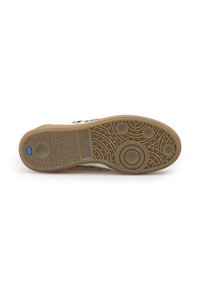 Suola di scarpa con grip in gomma strutturata, modelli circolari e triangolari, e un piccolo logo blu vicino al tallone su uno sfondo bianco.
