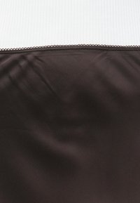 Tessuto marrone con una texture liscia e una sottile lucentezza, caratterizzato da un bordo ondulato lungo la parte superiore su uno sfondo bianco a righe.
