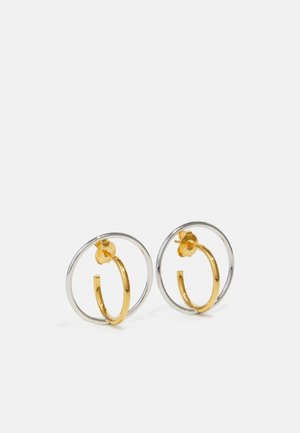 Zwei Creolen mit einem silbernen äußeren Kreis und einem goldenen inneren Ring, die eine Mischung aus glänzenden Metalloberflächen und kreisförmigen Formen zeigen.
