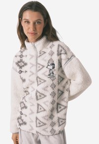 Biały polarowy sweter z geometrycznymi szarymi wzorami, z zamkiem przy kołnierzu oraz grafiką Snoopy. Miękka faktura, długie rękawy i luźny krój.