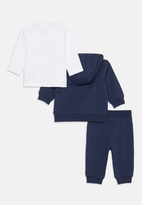 Set oblek za otroke iz bombaža, ki vključuje belo srajco z dolgimi rokavi, navy modro kapuco z dolgimi rokavi in navy modre trenirke z rebrastimi manšeti.