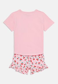 T-shirt en coton rose à manches courtes associé à un short blanc avec un imprimé cerise et un ourlet volanté. Design simple et ludique.