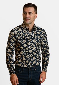 Marineblauwe overhemd met lange mouwen met een crèmekleurig bloemenpatroon, button-down kraag en slim fit ontwerp, gecombineerd met donkere denim jeans.