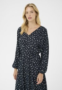 Long-sleeve navy dress with a V-neck and floral print, featuring a cinched waist and flowing skirt. Soft fabric with a smooth texture.