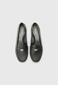 Zwarte leren loafers met een gouden MK-logo, een gestructureerd oppervlak en een gladde binnenkant met perforaties voor ademend vermogen.