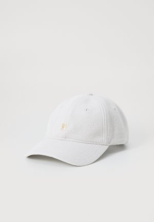 White fleece cap with rounded crown, curved brim, and a gold emblem on the front. Features stitching details and ventilation eyelets.