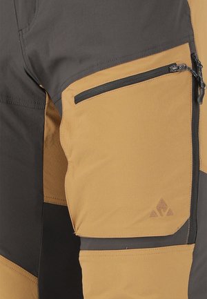 Pantalons cargo tactiques avec un mélange de panneaux gris foncé et jaune moutarde, tissu durable, poche zippée et détail de logo dans le coin inférieur.