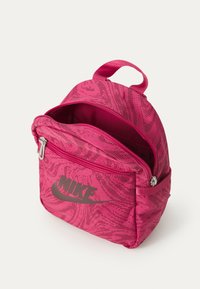 Rózsaszín Nike hátizsák, texturált dizájnnal, dupla cipzáras rekeszekkel és elöl logóval. A könnyű hordozhatóság érdekében felső fogantyúval rendelkezik.