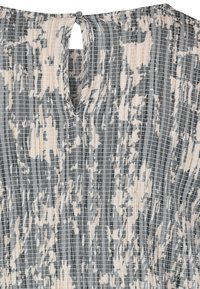 Strukturierter Kleidungsstoff in Grau, Weiß und Beige mit einem karierten Muster. Verfügt über eine Schlüssellochöffnung im Rücken mit einem Knopfverschluss.