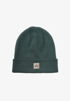 Neulepipo syvässä vihreässä, jossa on käännettävä reuna. Siinä on suorakulmainen beigepatch, jossa on ristikkäisten työkalujen emblem. Pehmeä rakenne.