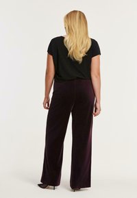Zwarte top met korte mouwen gecombineerd met donkerpaarse wijde broek, met een zachte textuur en een gladde afwerking. Hielenschuhe in zwart maken de look compleet.