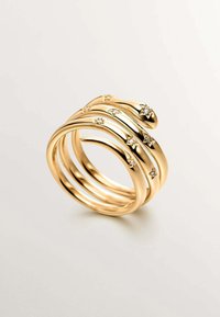 Anillo en tono dorado, con capas y un diseño ondulado, adornado con pequeñas piedras decorativas. Textura lisa con acabado pulido, que muestra una estética moderna.