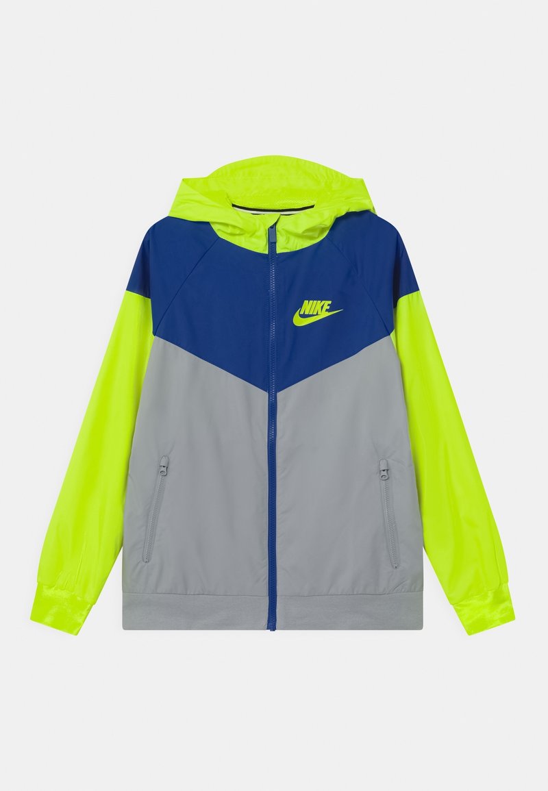 Giacca windbreaker Nike con cappuccio. Presenta un design a blocchi di colore in blu navy, giallo brillante e grigio. Materiale leggero con tasche con zip.