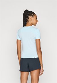 T-shirt atlético de manga curta, azul claro, com um design ajustado, feito de um tecido suave. As costas apresentam um painel texturizado em contraste.