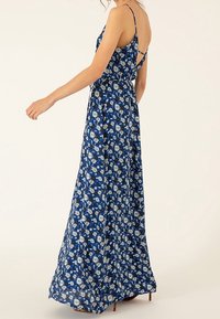 Robe maxi fleurie bleue avec de fines bretelles, dotée d'un corsage ajusté et d'une jupe fluide. Fabriquée dans un tissu léger au toucher doux.