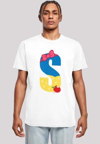 Balta t-krekla ar lielu zilu "S" un rozā lentīti, dzeltena fona ar zvaigznēm un sarkanas ābolu grafiku apakšā.