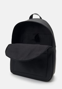 Svart ryggsäck i slätt material med rundad form, topphandtag och ett rymligt innanför med klaffstängning.