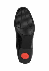 Schwarze Leder Schuhsohle mit strukturiertem Gummi für Halt, mit einem roten kreisförmigen Logo mit der Aufschrift "Komfort". Gerundete Zehenform und gebogene Seitenlinie.