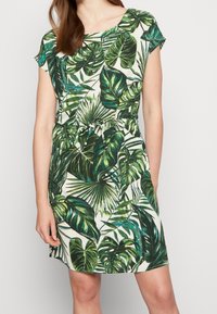 Šaty s krátkými rukávy a zeleným vzorem listů, s vázáním v pase, na krémovém pozadí a vyrobené z měkké tkaniny.