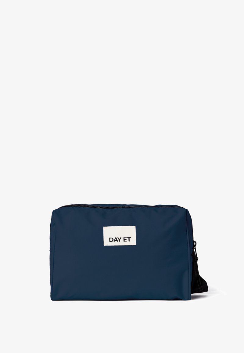 Borsa in nylon blu navy dalla forma rettangolare, con un'etichetta in tessuto bianco che riporta la scritta "DAY ET" e una cerniera nera. Design semplice e funzionale.