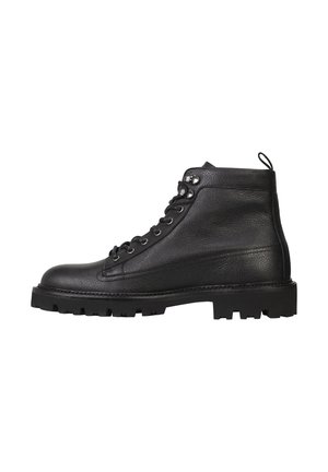Botas de senderismo de cuero negro con un acabado texturizado, que presentan ojales de metal, cordones, una cinta de agarre y una suela de goma resistente y con patrón.