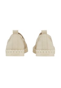 Scarpe slip-on in suede beige con accenti perforati, suola testurizzata e dettagli di cucitura visibili. Il marchio è impresso sul tallone.