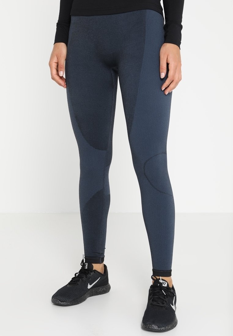 Námořnické legíny vyrobené z texturované, pružné látky s akcenty panelů. Mají přiléhavý design a jsou kombinovány s černými sportovními botami.