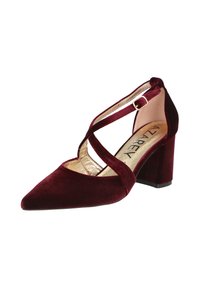 Zapato burdeos de terciopelo con tacón cuadrado y punta afilada, correas cruzadas y detalles de forro en tono dorado. Textura suave.