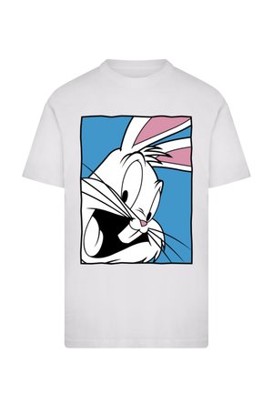 Bílé tričko s kreslenou tváří králíka s černým obrysem na růžovo-modrém pozadí. Králík má velké výrazné oči a vousky.