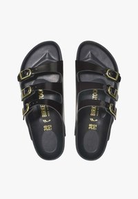 Zwarte slip-on sandalen met drie verstelbare banden, gouden gespen en een gestructureerde voetbed, met een maat 38 aanduiding aan de binnenzijde.