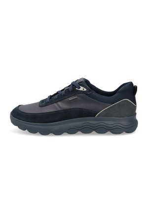 Zapatillas deportivas azul marino con un diseño elegante, parte superior de sintético suave, acentos texturizados y una suela de goma gruesa con patrones en forma de ola.