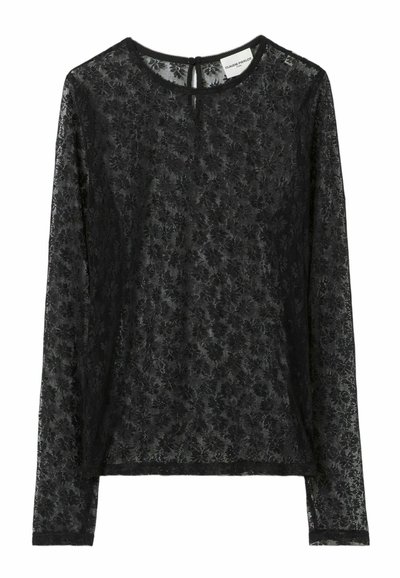 Top lungo in pizzo nero con maniche lunghe, caratterizzato da un motivo floreale, scollo rotondo e chiusura a goccia sul retro. Tessuto morbido e testurizzato.