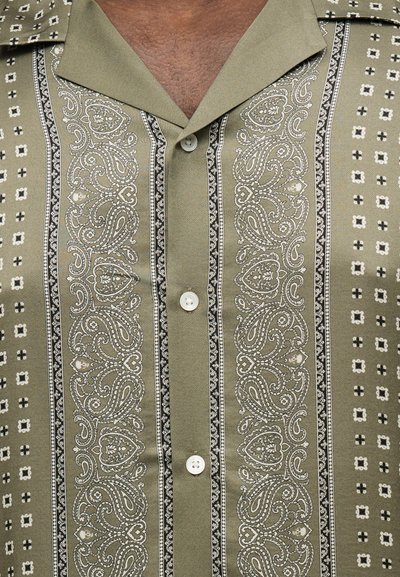 Πουκάμισο με βάση ελιάς πράσινο που διαθέτει κατακόρυφα λευκά και μαύρα μοτίβα πεϊσλεϊ και γεωμετρικά, εμπρόσθιο κλείσιμο με κουμπιά και ανοιχτό γιακά.