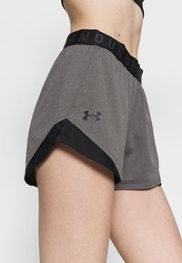 Šedé sportovní šortky s černým pasem, na kterém je nápis 'ARMOUR'. Černé detaily na lemu a malá loga na straně. Měkká látka.