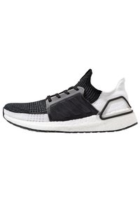 Czarnobiałe buty sportowe zdzianą cholewką, teksturowaną szaro-skalową częścią środkową i białą wyściełaną podeszwą; posiadają zakrzywiony czarny akcent na pięcie.