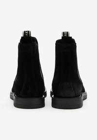 Svarta släta Chelsea-boots i mocka med texturerad yta, med elastiska sidopaneler och dragflikar, som vilar på en svart gummisula.