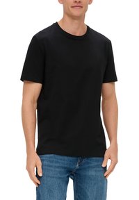 T-shirt en coton noir avec un col ras du cou et des manches courtes, présentant une texture lisse. Associé à un jean en denim bleu.