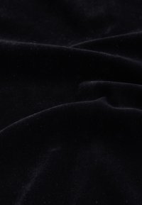 Tissu en velours noir à la texture douce, présentant un éclat subtil et de légers plis, créant une apparence lisse et luxueuse.