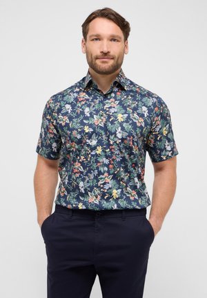 Camicia a maniche corte in tessuto blu scuro con un motivo floreale colorato. Presenta un colletto tradizionale e una chiusura con bottoni davanti.