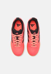 Zapatillas deportivas de color rosa brillante con detalles y cordones negros, con una parte superior sintética texturizada y suela de goma, diseñadas para uso atlético.
