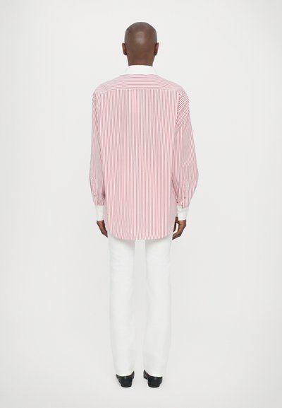 Red and white striped long-sleeve shirt with a white collar, paired with white pants. Smooth fabric with a relaxed fit.