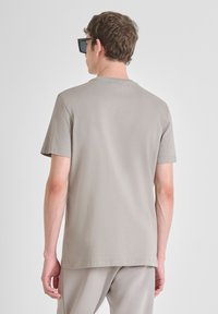 Camiseta de manga corta y cuello redondo en algodón gris claro, con una textura suave y detalles de costura mínimos.