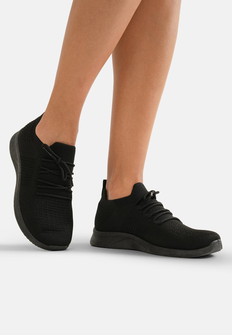 Zwarte gebreide sportieve schoenen met een textuur bovenkant, ronde neus, elastische veters en een gevoerde zool. Ze bieden een aansluitende pasvorm rond de enkel.