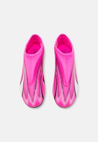 Scarpe slip-on rosa con una tomaia in tessuto morbido e elasticizzato, caratterizzate da strisce dinamiche in bianco e nero per un accento e una vestibilità aderente.