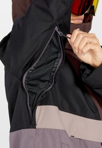 Wasserabweisende Jacke mit einem Farbblockdesign in Schwarz, Braun und Helllila, ausgestattet mit einer Reißverschluss-Taschenbelüftung und einer Netzfutter.