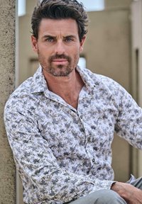 Weißes Hemd mit einem grauen Blättermuster, langen Ärmeln und einem Knopfkragen. Der Stoff hat eine glatte Textur und einen dezenten Glanz.