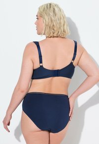 Navyblauwe bh en set met hoge taille slip in een gladde stof. Beschikt over verstelbare banden en een haak-en-oog sluiting aan de achterkant. Geen patronen.