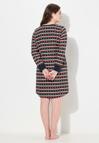 Abito in tessuto blu navy con strisce orizzontali rosse, verdi e bianche, decorato con motivi a cuore. Maniche lunghe, orlo arrotondato, lunghezza a metà coscia.