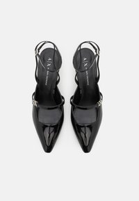 Melnas lakota ādas slingback kurpes ar stuviem purngaliem, plānām potītes siksnām un maziem sudraba tonī izstrādājumiem. Gluda virsma, elegants dizains.
