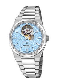 Silverfärgad klocka i rostfritt stål med en ljusblå mönstrad urtavla, synlig mekanism och safirglas. Har pinnmarkörer för timmar och en polerad finish.